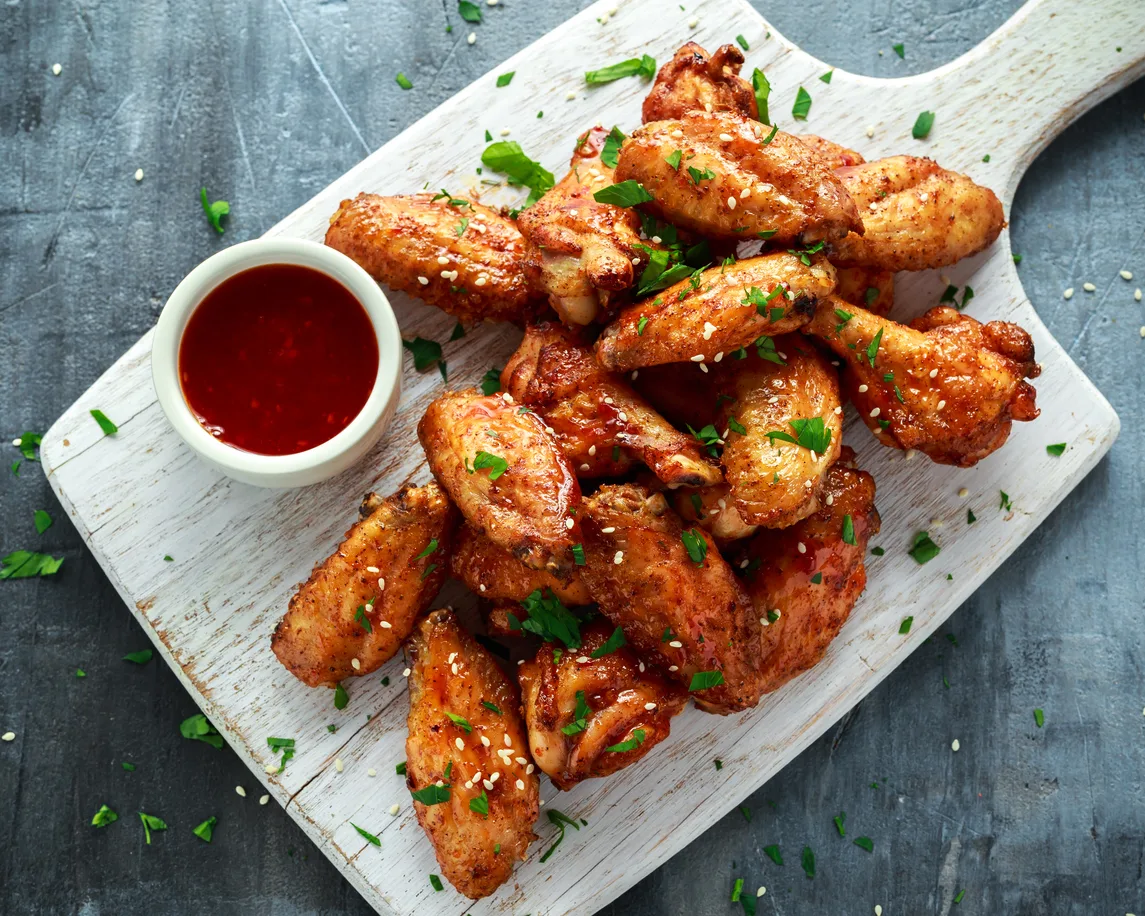 A platter of glazed chicken wings with dipping sauce